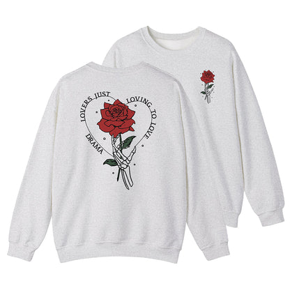 Light gray DRAMA Lovers Crewneck with a hand holding a red rose, green leaves, and “Lovers Just Loving to Love” lettering on the back.